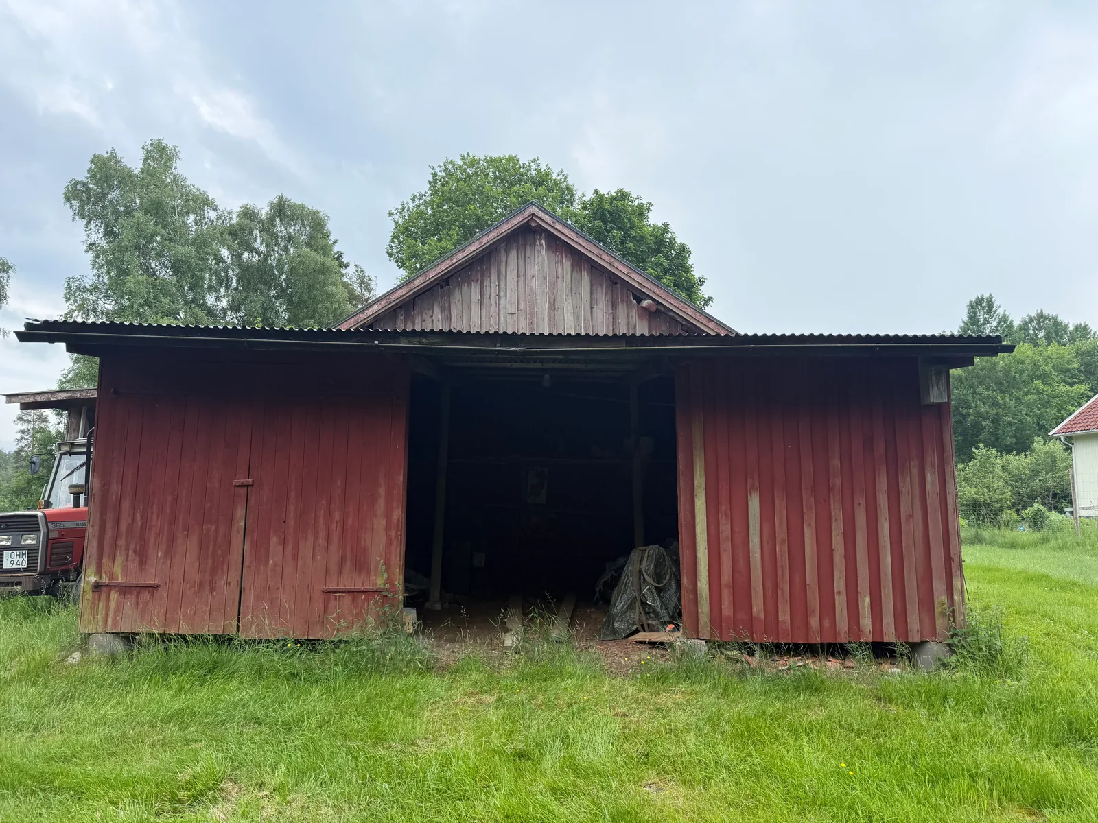 Ladugårdens framsida före fasadmålning, med sliten och blekt träpanel.